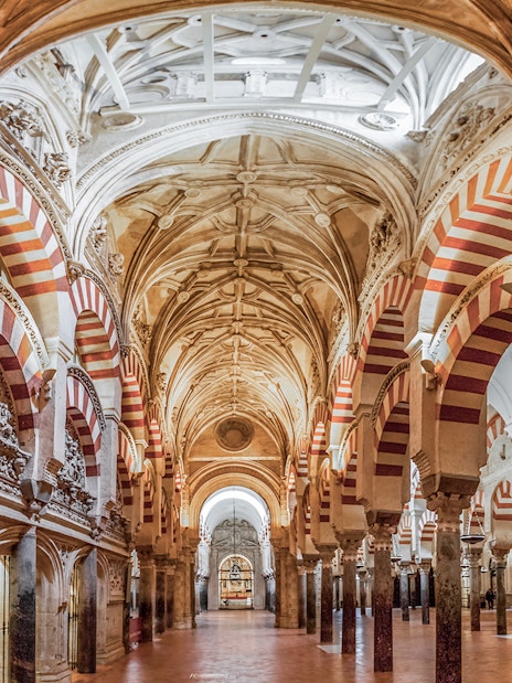 Interiors of the Cordoba Mosque-Cathedral prayer hall with red and white arches.