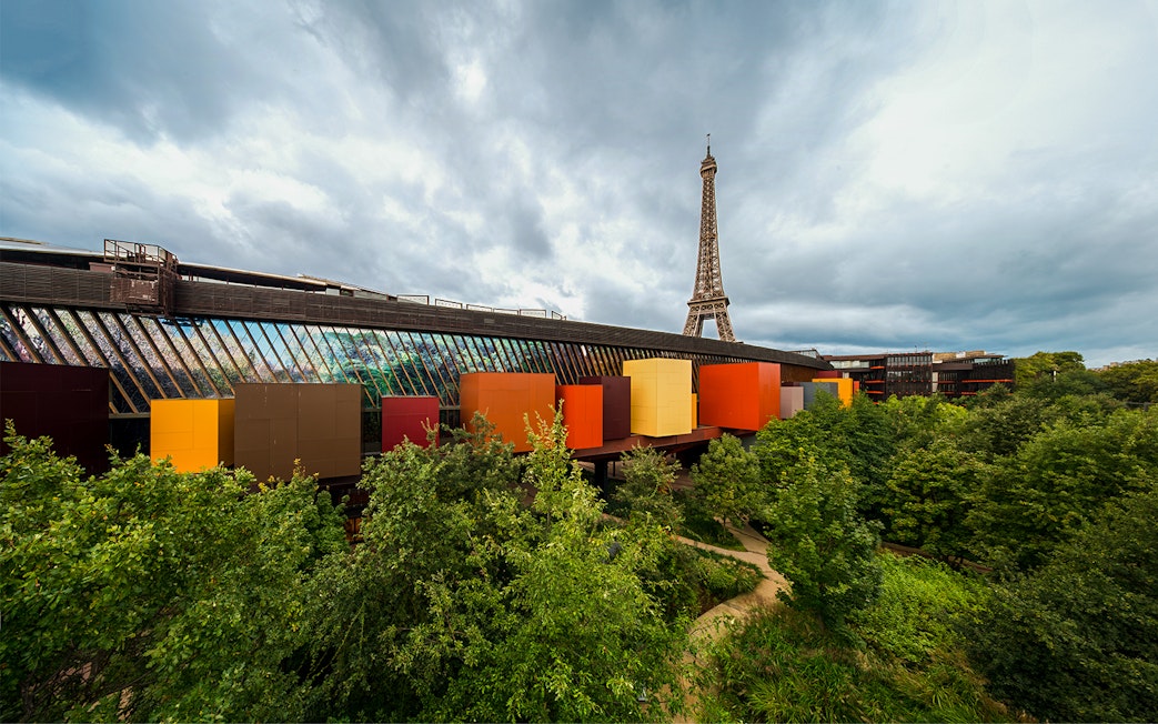 Quai Branly Museum exterior with colorful facade, Eiffel Tower in background, Paris.