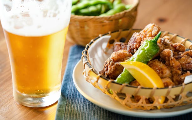 Beer with fried chicken and peppers in a local bar setting.