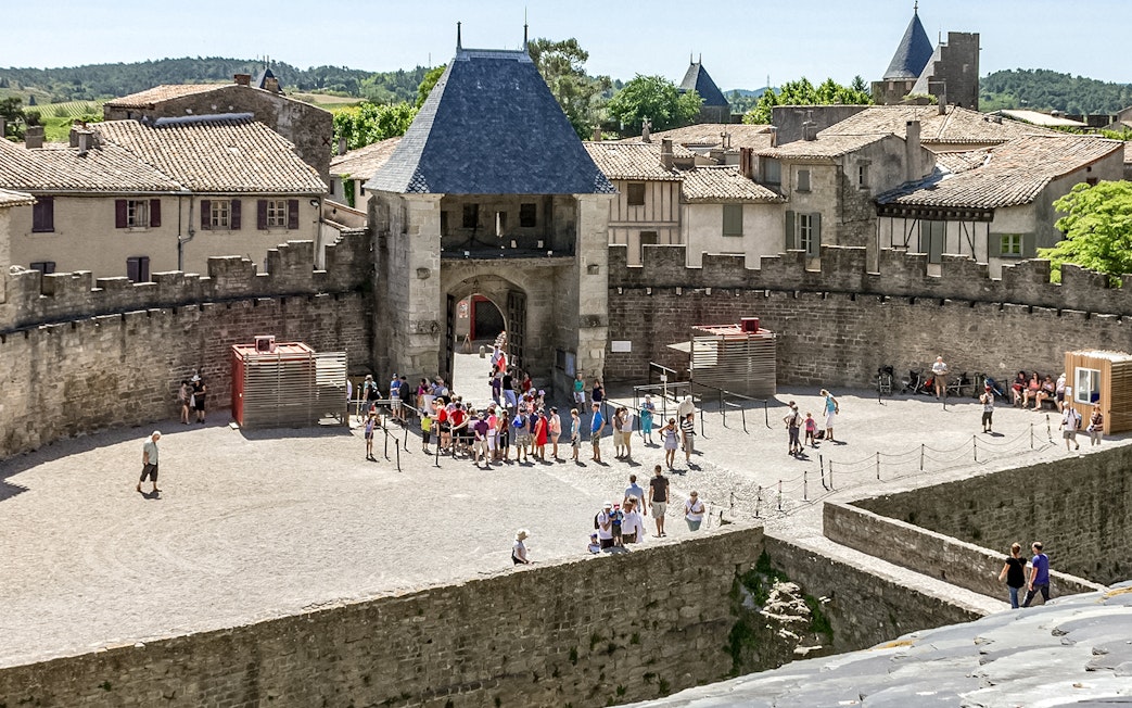 Visitors exploring the courtyard of Comtal Castle in Cité de Carcassonne, France.