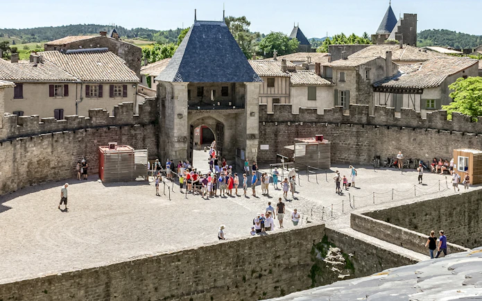 Visitors exploring the courtyard of Comtal Castle in Cité de Carcassonne, France.