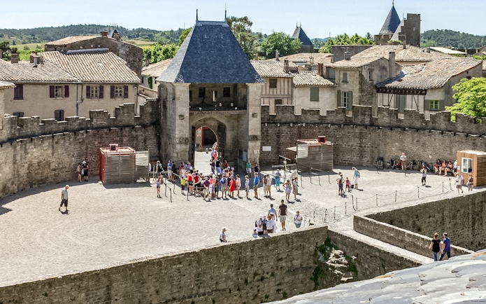Visitors exploring the courtyard of Comtal Castle in Cité de Carcassonne, France.