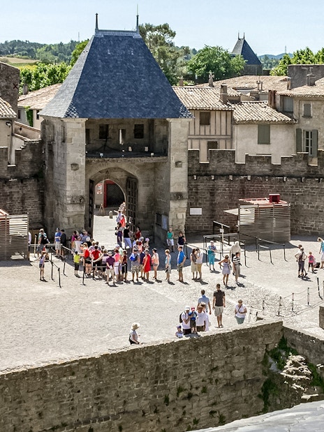 Visitors exploring the courtyard of Comtal Castle in Cité de Carcassonne, France.