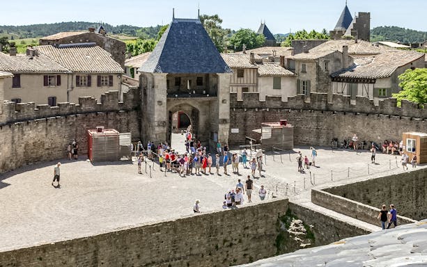 Visitors exploring the courtyard of Comtal Castle in Cité de Carcassonne, France.