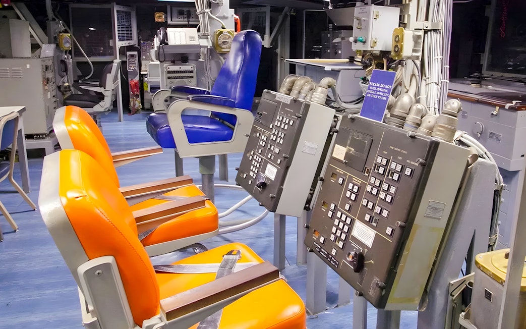 Control room inside USS Missouri with orange and blue chairs.