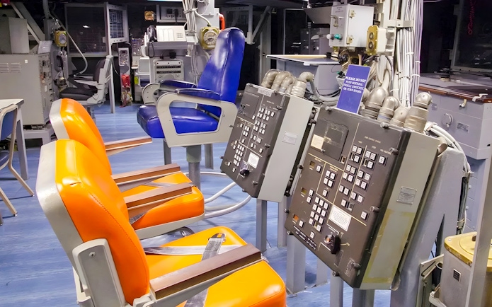 Control room inside USS Missouri with orange and blue chairs.