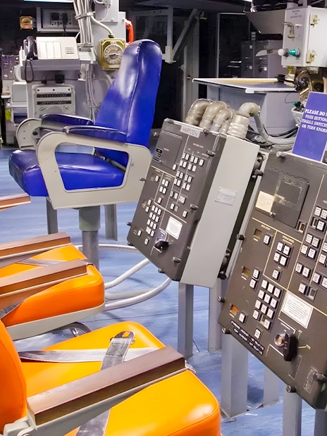 Control room inside USS Missouri with orange and blue chairs.