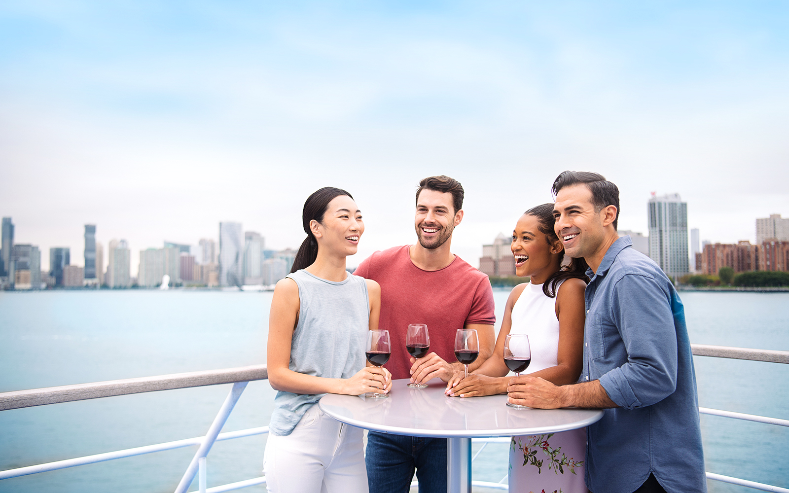 Group enjoying wine on a New Jersey Signature Cruise with city skyline in the background.