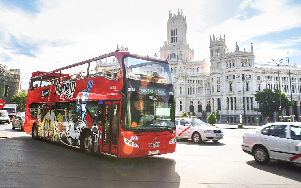 Hop-on-hop-off bus passing by the Palacio de Cibeles in Madrid.