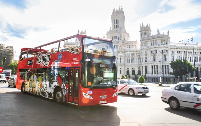 Hop-on-hop-off bus passing by the Palacio de Cibeles in Madrid.