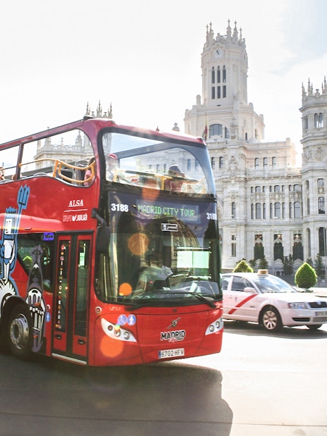 Hop-on-hop-off bus passing by the Palacio de Cibeles in Madrid.