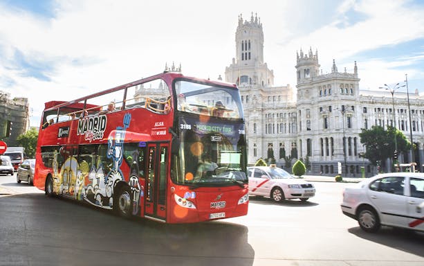 Hop-on-hop-off bus passing by the Palacio de Cibeles in Madrid.