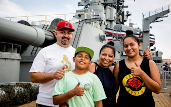Family enjoying a self-guided tour on a historic battleship deck.