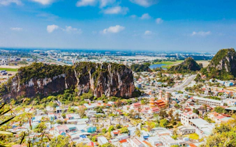 Panoramic view of Da Nang cityscape from Marble Mountains, Vietnam, with lush greenery and urban landscape.