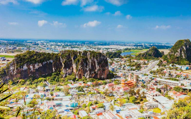 Panoramic view of Da Nang cityscape from Marble Mountains, Vietnam, with lush greenery and urban landscape.