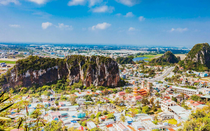 Panoramic view of Da Nang cityscape from Marble Mountains, Vietnam, with lush greenery and urban landscape.