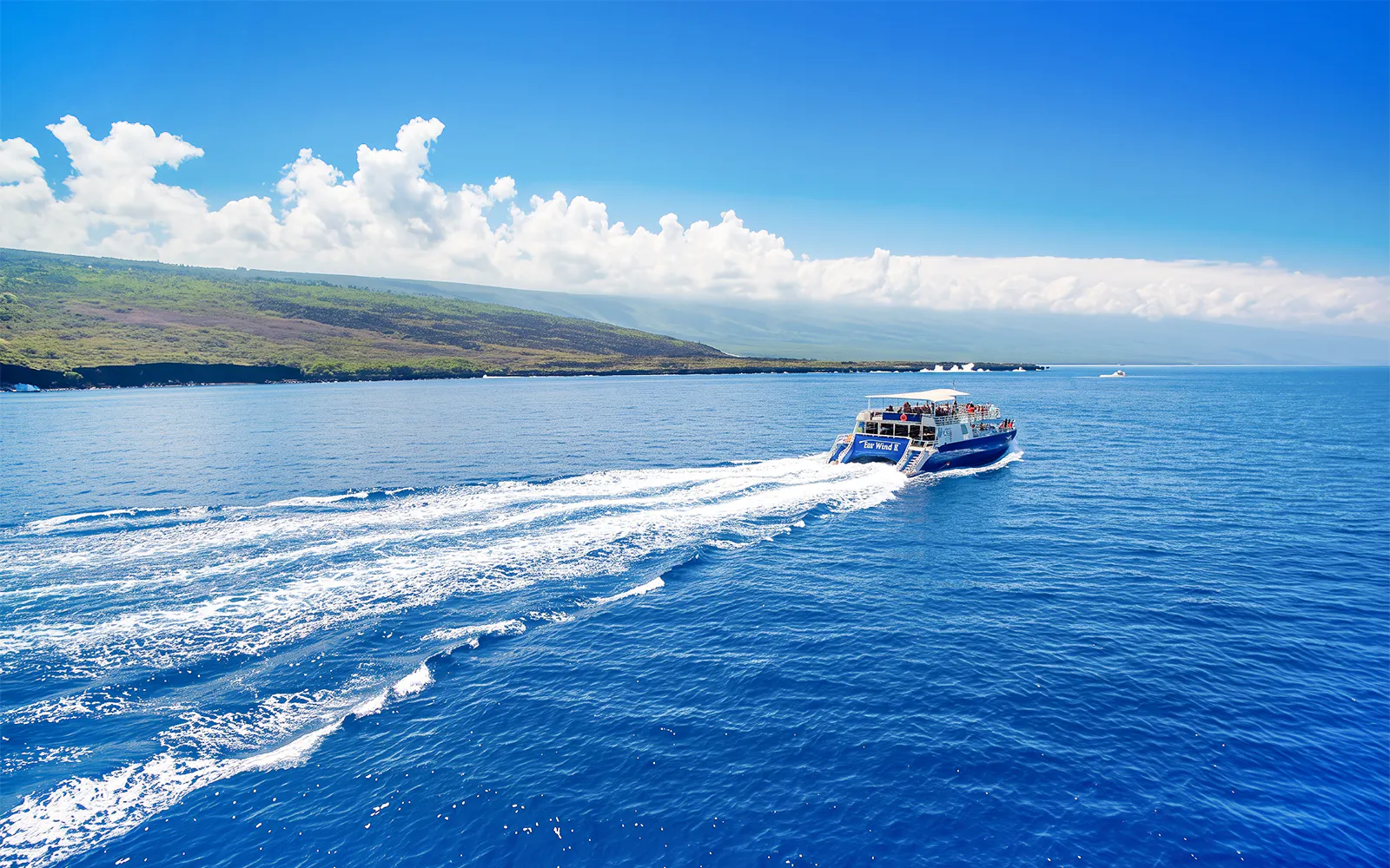 Boat cruising on Kealakekua Bay, Hawaii, with scenic coastline in the background.