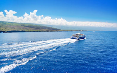 Boat cruising on Kealakekua Bay, Hawaii, with scenic coastline in the background.