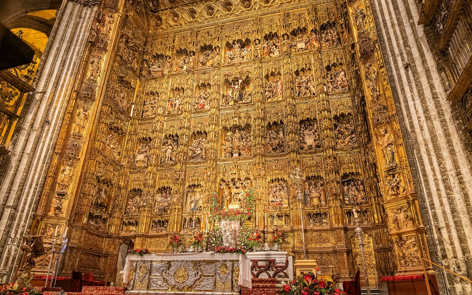 Altar piece of Seville Cathedral with intricate gold carvings and religious figures.