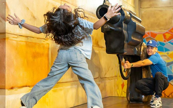 Visitor interacting with a giant illusionary gun at the Big Fun Museum, Barcelona.