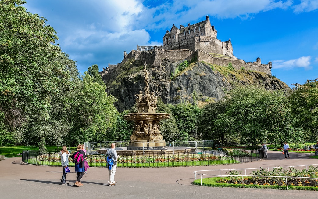 Visitors walking near the Ross Fountain with Edinburgh Castle in the background.