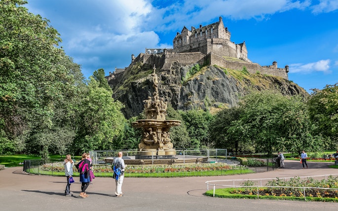 Visitors walking near the Ross Fountain with Edinburgh Castle in the background.