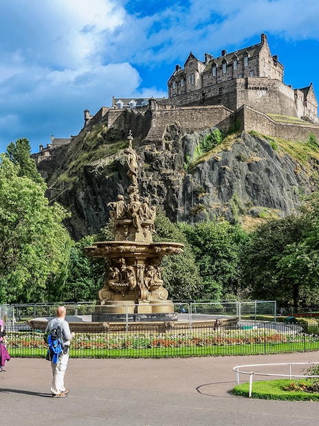 Visitors walking near the Ross Fountain with Edinburgh Castle in the background.