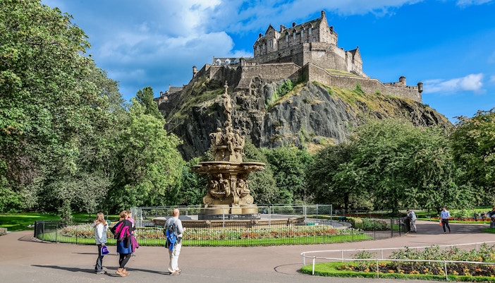 Visitors walking near the Ross Fountain with Edinburgh Castle in the background.