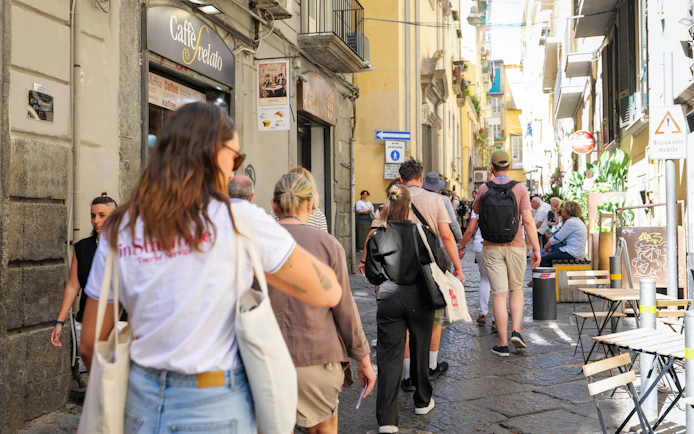 Tourists walking through a narrow street in Naples near Sansevero Chapel.
