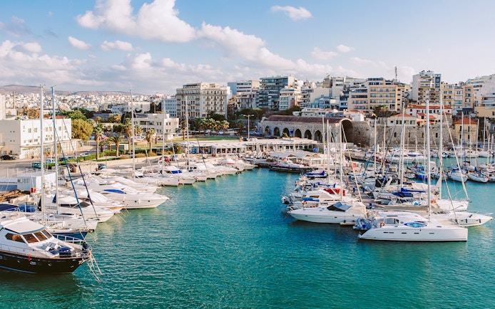Heraklion marina with yachts and cityscape, part of the Hop-On Hop-Off Sightseeing Bus Tour.