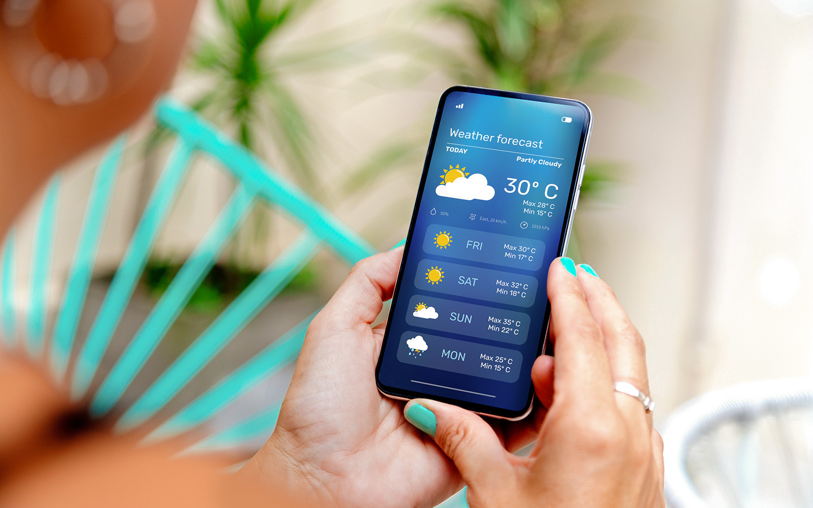 A person checking out a weather forecast app on her mobile phone at home.