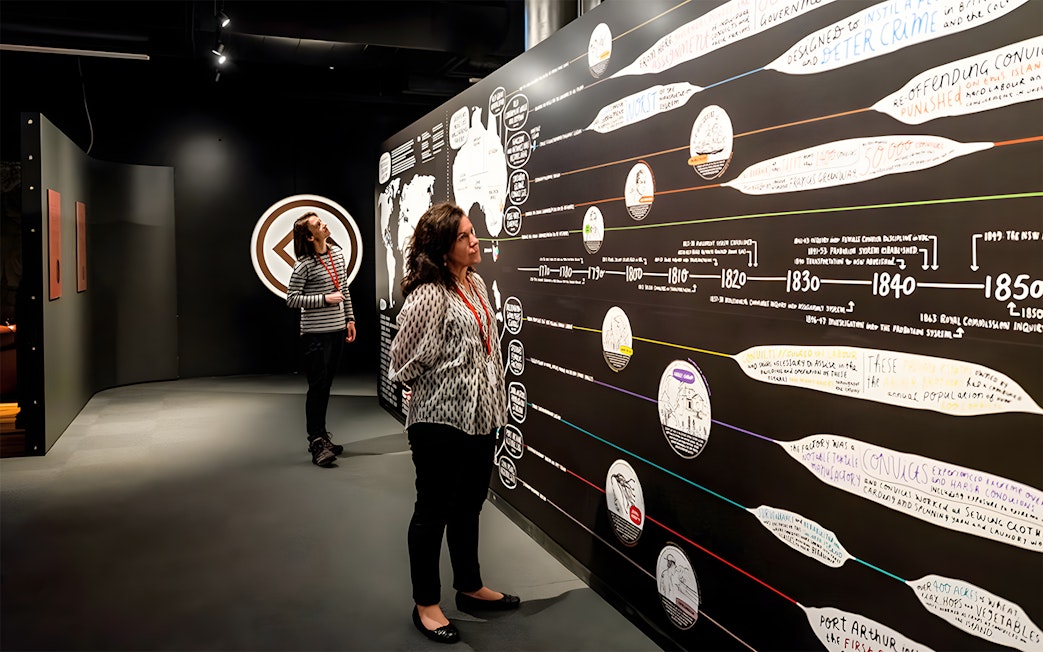 Visitors exploring historical timeline exhibit at Port Arthur museum.