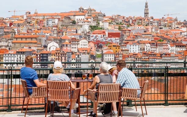 Tourists enjoying a view of Porto's historic cityscape from a terrace in WOW Porto Cultural District.