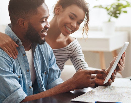Couple planning vacation with a world map and travel brochures.