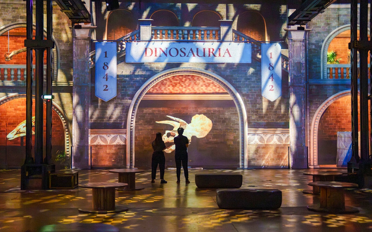 Visitors viewing dinosaur projections at Prehistoric Planet exhibition, Atelier des Lumières.