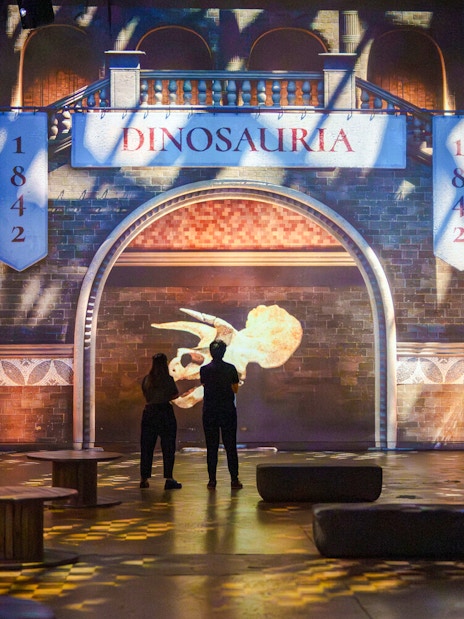 Visitors viewing dinosaur projections at Prehistoric Planet exhibition, Atelier des Lumières.
