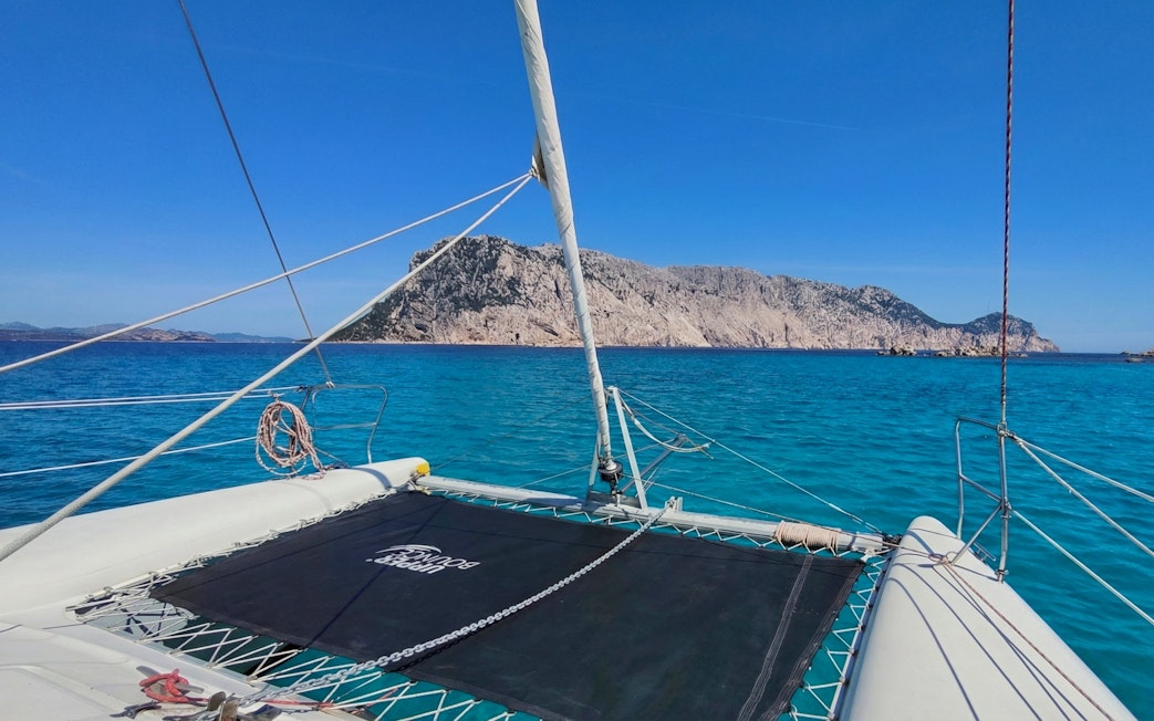 Catamaran sailing towards Tavolara Island, Sardinia, with clear blue waters.