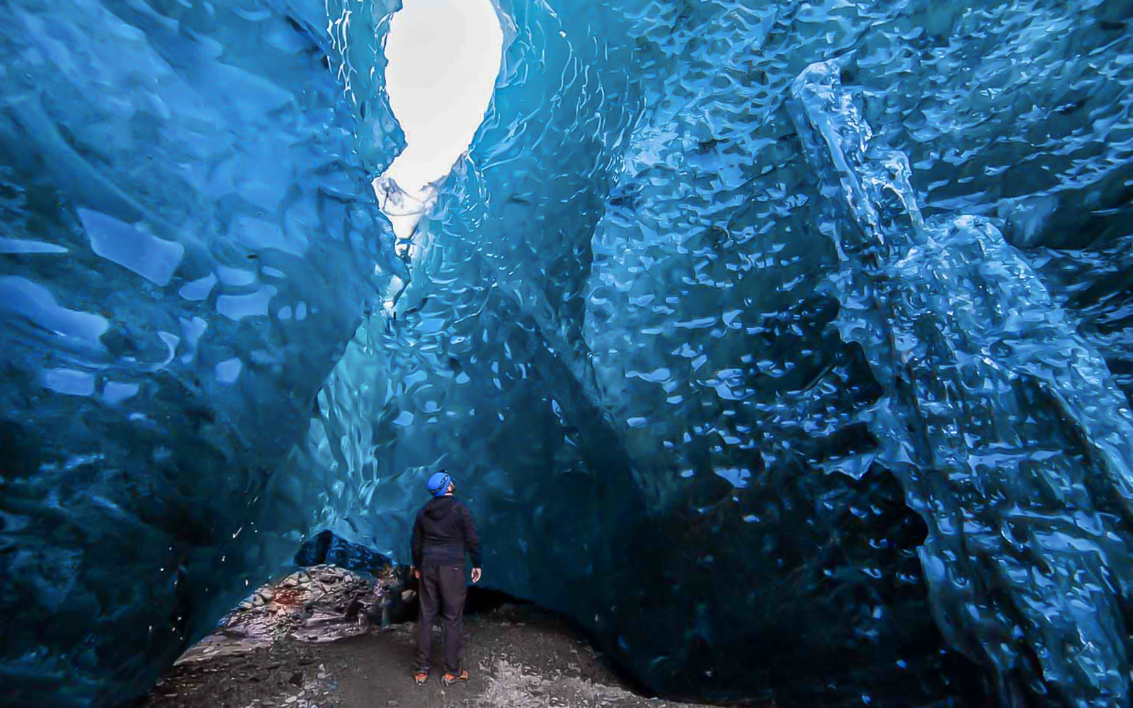 Person exploring inside a blue crystal ice cave.