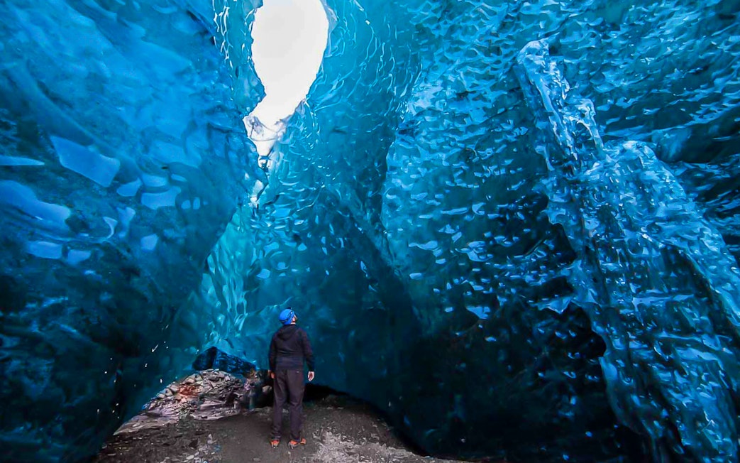 Person exploring inside a blue crystal ice cave.
