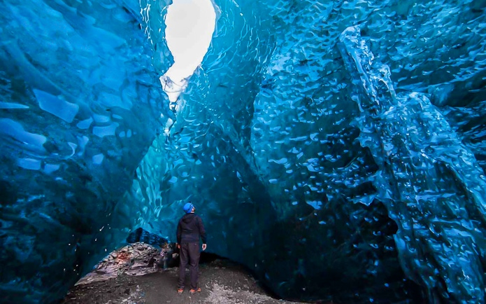 Person exploring inside a blue crystal ice cave.