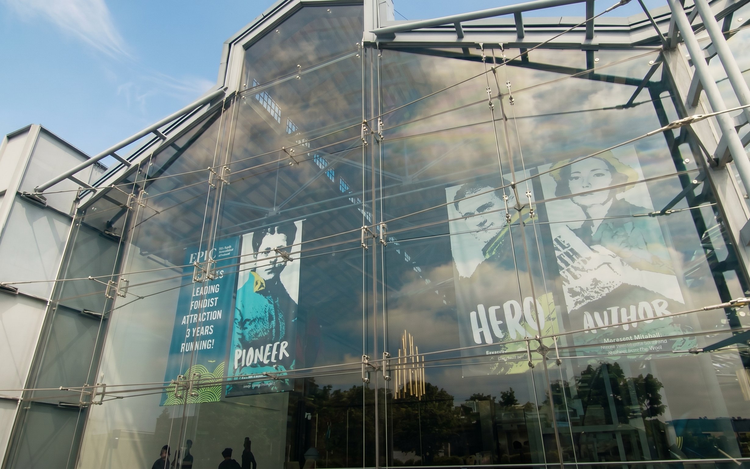 Glass facade of EPIC Museum with posters of historical figures.