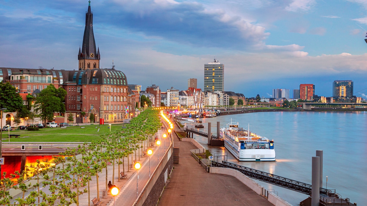Rhine Promenade at sunset with cityscape and river cruise ship, Dusseldorf, Germany.