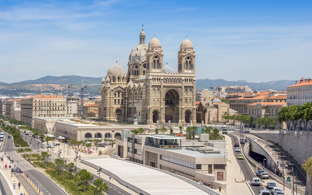 Historic Cathedral de la Major in Marseille with cityscape and distant hills.