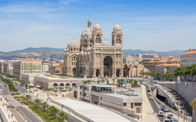 Historic Cathedral de la Major in Marseille with cityscape and distant hills.