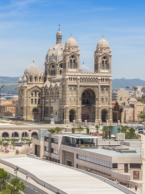 Historic Cathedral de la Major in Marseille with cityscape and distant hills.