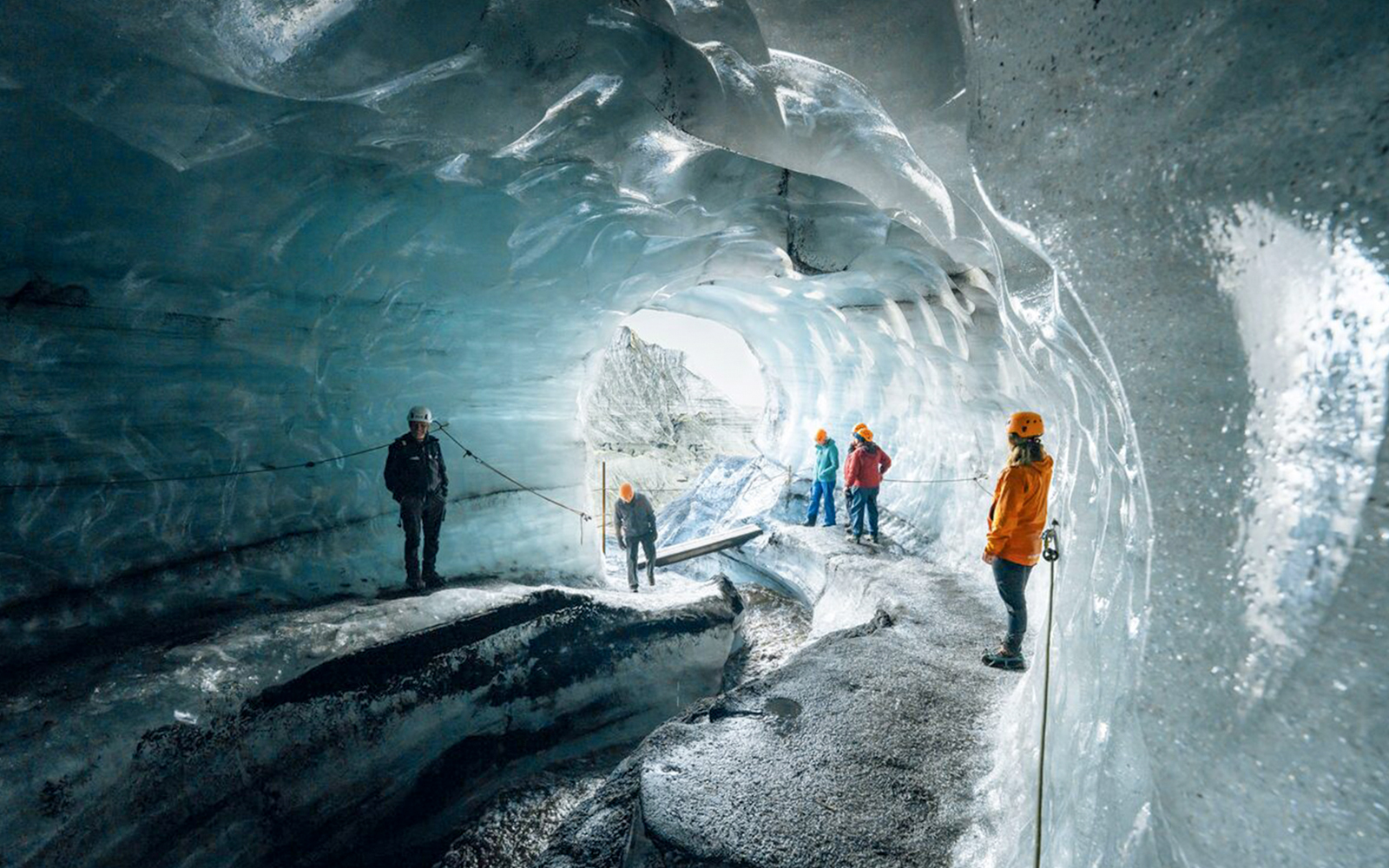 Tour guide assisting guests inside Katla Ice Cave, Iceland.
