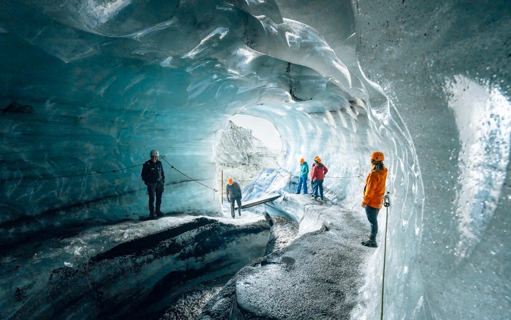 Tour guide assisting guests inside Katla Ice Cave, Iceland.