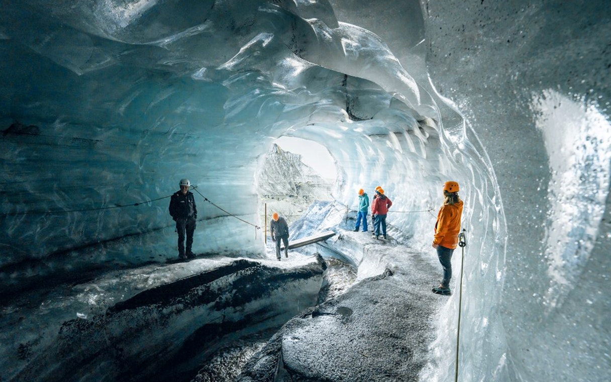 Tour guide assisting guests inside Katla Ice Cave, Iceland.