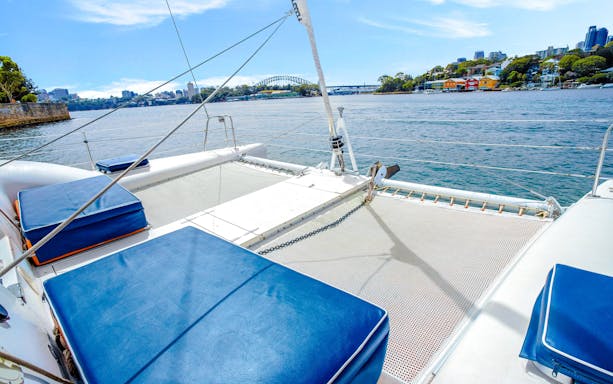 Luxury catamaran deck with Sydney Harbour Bridge view during Vivid Sydney cruise.