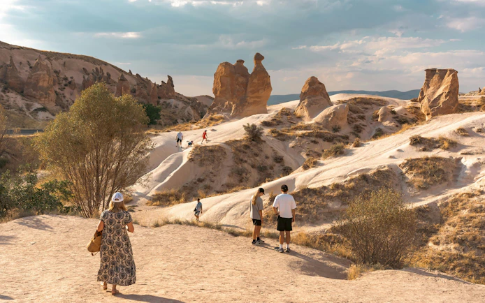 Visitors exploring Imagination Valley with Camel Rock formation in Cappadocia.